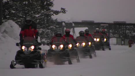 a snowmobile train heads through deep snow in yellowstone national park