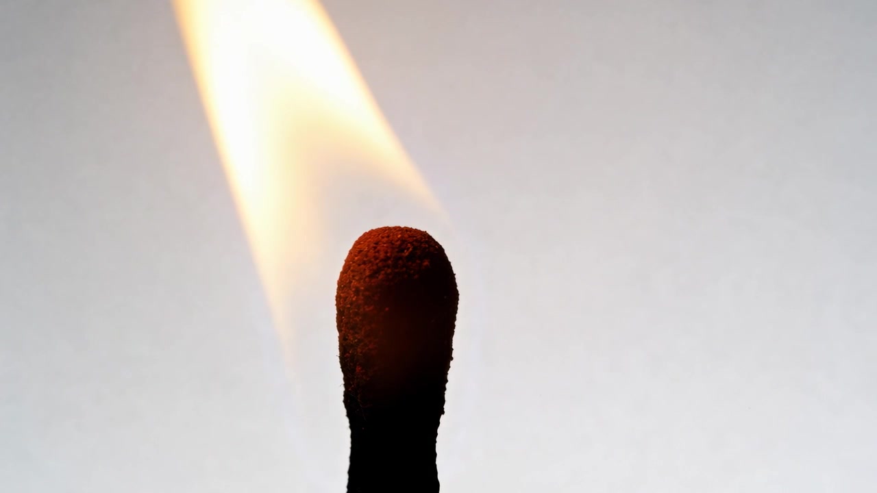 Allumant une allumette, une flamme vive s'enflamme, la tête d'allumette brûle en gros plan en studio montrant la pointe de phosphore
