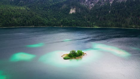 drone shot reveals beautiful island in lake eibsee at the base of mountain zugspitze, scenic lake in the mountains, germany