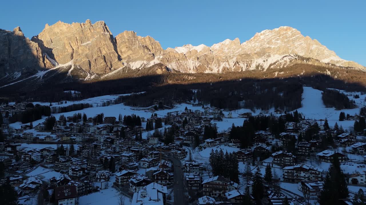 Drone shot of Cortina ski slopes at sunrise with snow-covered Dolomites before Olympics 2026