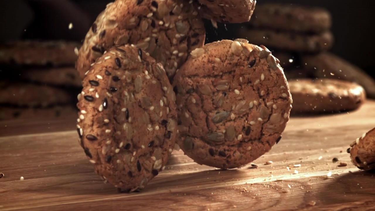 Rallentatore di biscotti con semi che cadono su un tavolo di legno