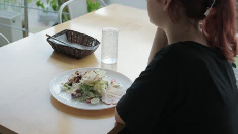 woman eating salad in a cafe