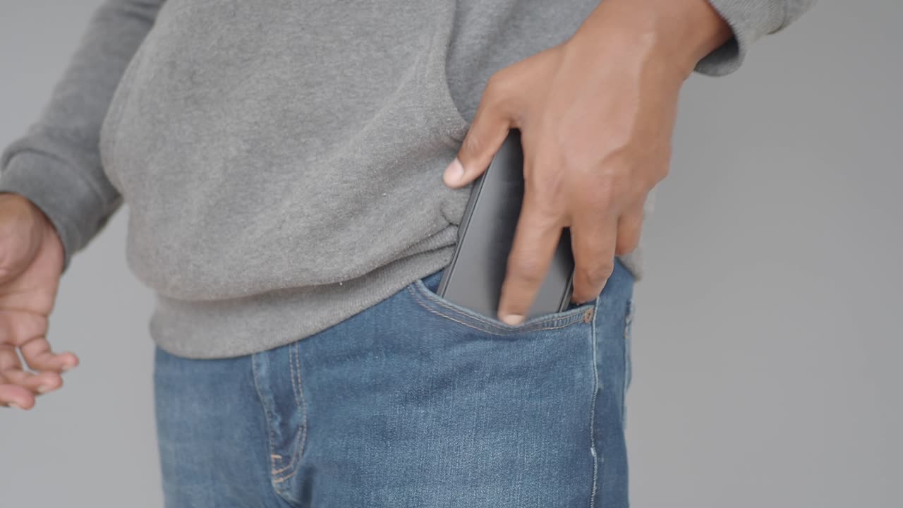 Person putting a smartphone into their jeans pocket