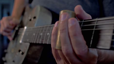 hombre tocando una vieja guitarra resonadora metálica con tobogán cerca del cuello