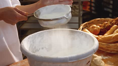 Female-baker-sifting-flour-through-a-sieve