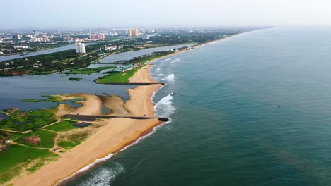 drone footage of beach with a backwater opening to it with a city skyline with high rises in backdrop