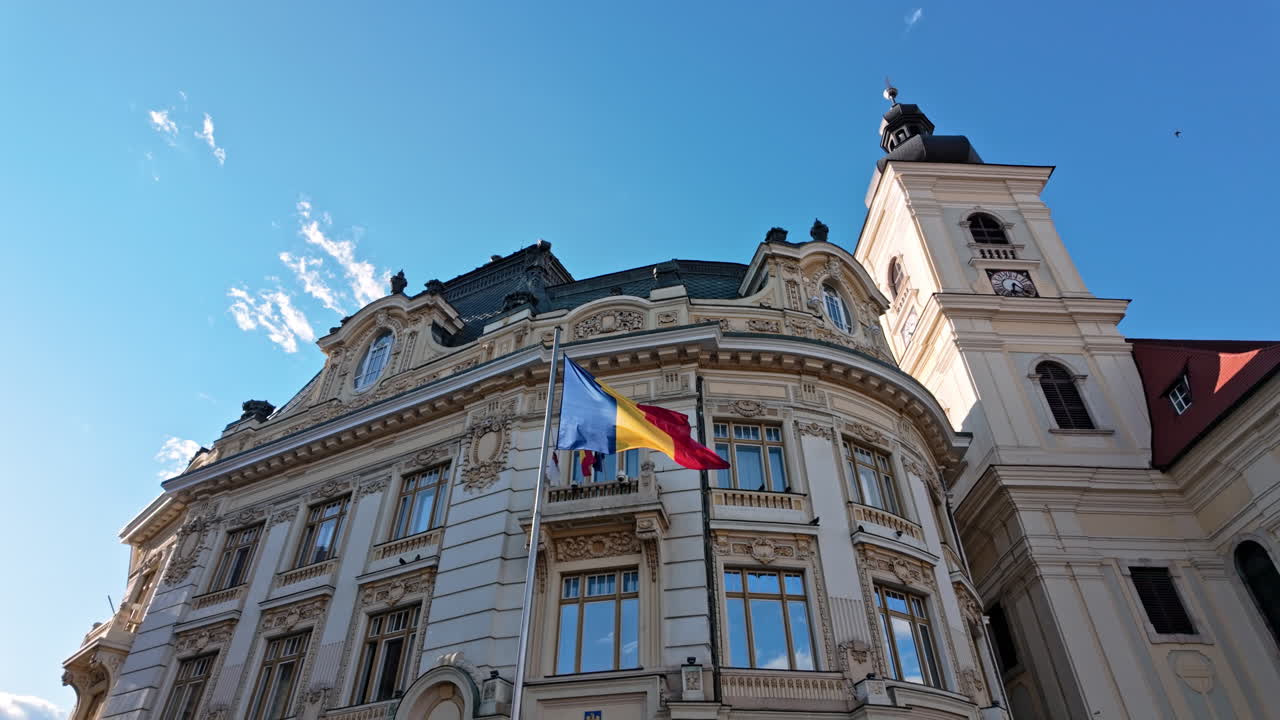 Sibiu City Hall bathed in sunlight with blue sky, evokes elegance and history