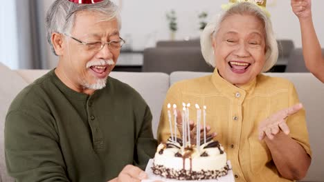 an elderly couple enjoys a birthday celebration with cake and candles in a cozy home setting, filled with laughter and joy