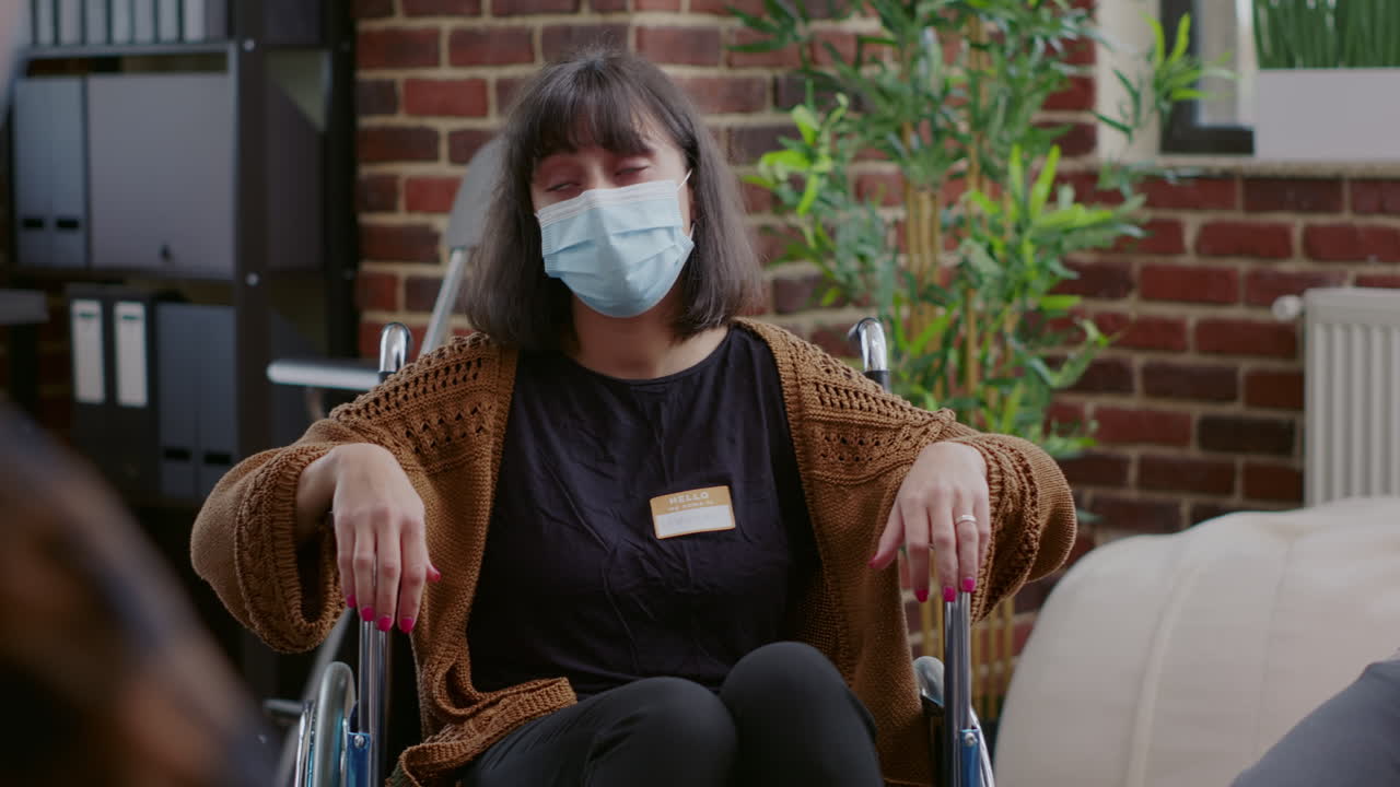 Close up of woman with face mask sitting in wheelchair at aa group meeting