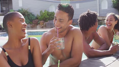 grupo de diversos amigos masculinos y femeninos con bebidas riendo en la piscina