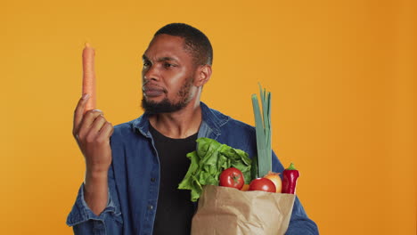 vegan guy looking closely at a carrot to ensure its best shape