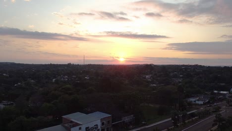 Aerial-view-of-the-town-of-San-Ignacio,-Belize,-with-a-beautiful-golden-sunset-on-the-horizon