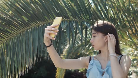 woman taking selfie under palm trees