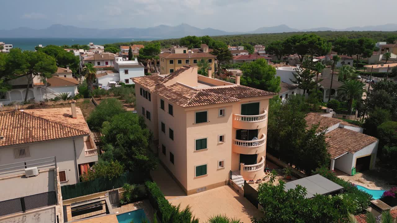 A drone shot highlighting a uniquely styled block building in Can Picafort, Mallorca, showcasing its distinctive architecture and urban setting.
