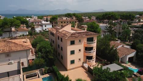 a drone shot highlighting a uniquely styled block building in can picafort, mallorca, showcasing its distinctive architecture and urban setting.