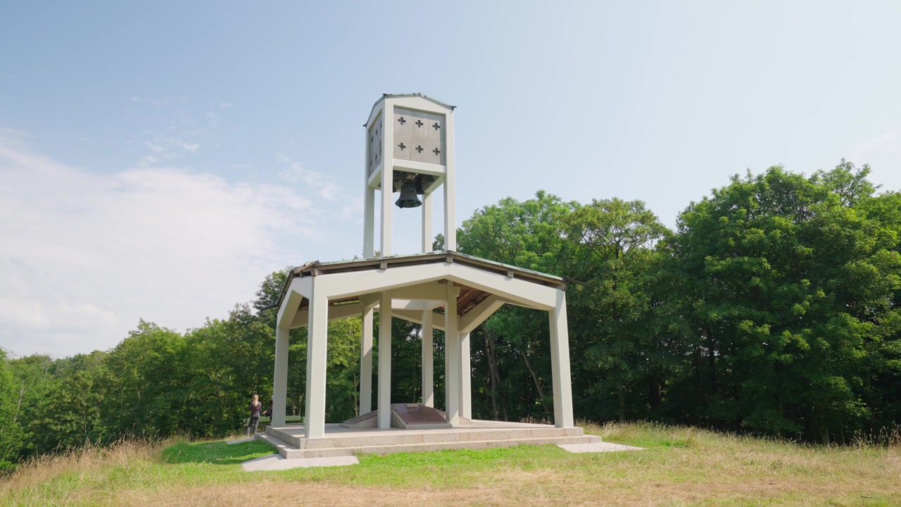 Campanile e padiglione commemorativo di Skamlingsbanken su una collina erbosa in Danimarca, un luogo di ritrovo nazionale storico circondato da boschi sotto un luminoso cielo estivo