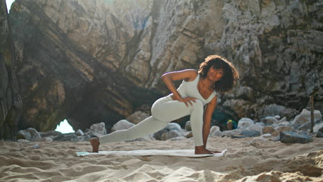 woman standing utthita parsvakonasana pose on beach. girl training yoga asana.