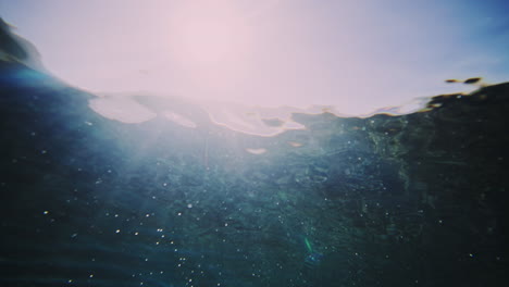 bajo el agua hipnotizante vista de las distorsiones brillantes en forma abstracta de la ola chocando contra el barril