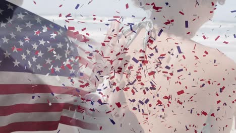 Animation-of-american-flag-and-confetti-over-african-american-couple-at-beach