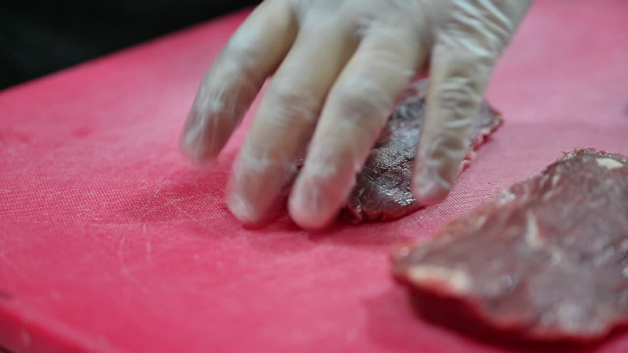 4k: Chef cutting raw meat on a cutting board in a professional kitchen-1