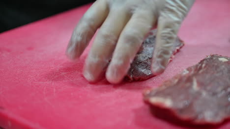 4k:-Chef-cutting-raw-meat-on-a-cutting-board-in-a-professional-kitchen-1