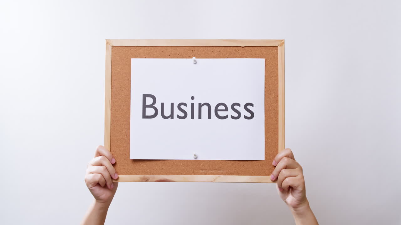 Naisen käsi esittelee paperia, jossa lukee "Business", valkoisella studiotaustalla ja tilaa tekstille.