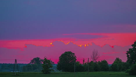 Stormy-clouds-flowing-in-sky-lit-by-red-sunset,-time-lapse-view