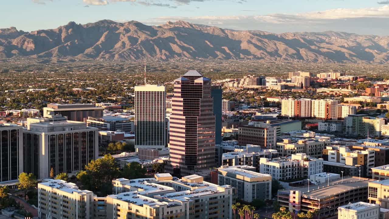 Straight push in drone shot towards downtown Tucson, Arizona near sunset with Catalina Mountains in background