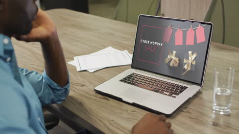 African-american-man-at-table-using-laptop,-online-shopping-on-cyber-monday,-slow-motion