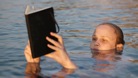 woman reading while floating in the sea