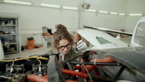 female aviation mechanic inspecting aircraft engine with flashlight
