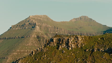 Person Standing on a Rocky Peak in a Vast Mountain Landscape