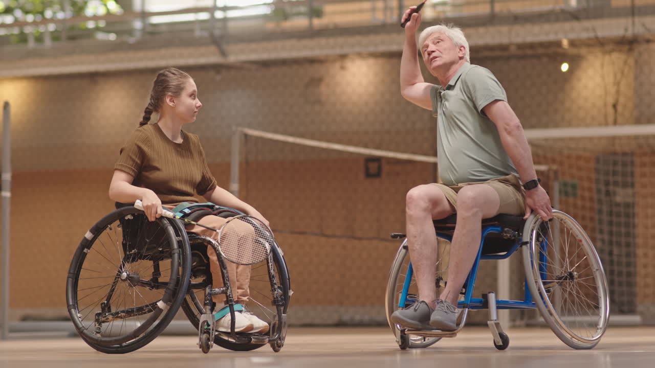 Man Teaching Girl in Wheelchair to Play Badminton