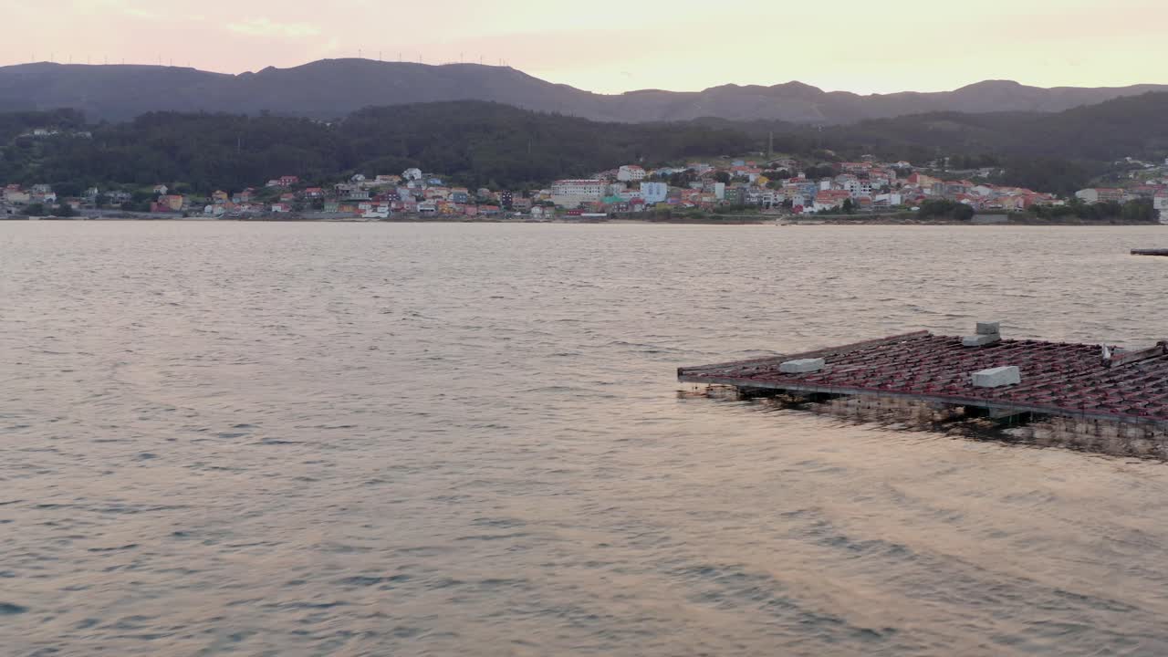 Galician coastline in background, as drone passes Mussel farm platform