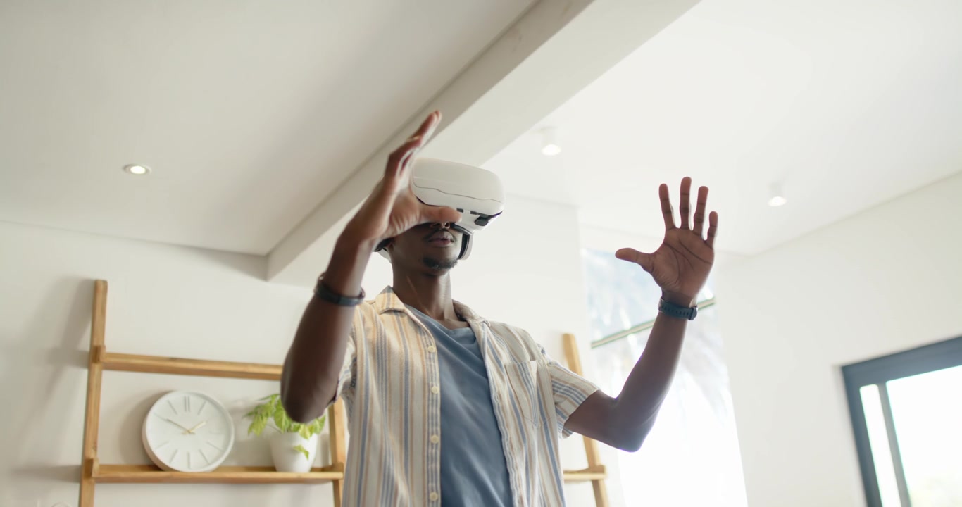 Afroamerikansk mand iført hvidt VR-headset, manipulerer objekter mens han udforsker en scene derhjemme.