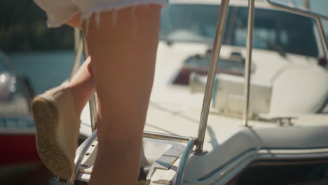 young long legged woman onboards modern yacht in sunny port closeup. passenger ready for sea cruise by fast motorboat. summer vacation at resort