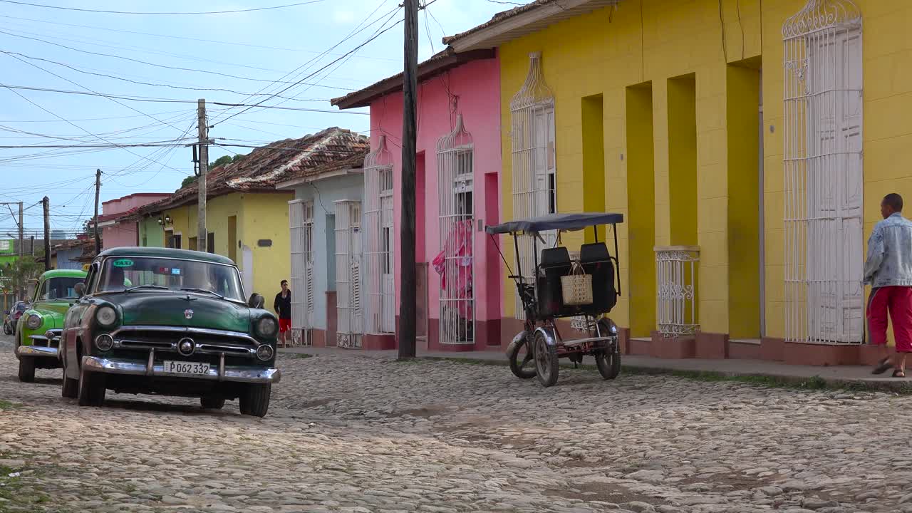 una hermosa foto de los edificios y calles adoquinadas de trinidad cuba con un viejo auto clásico pasando 2