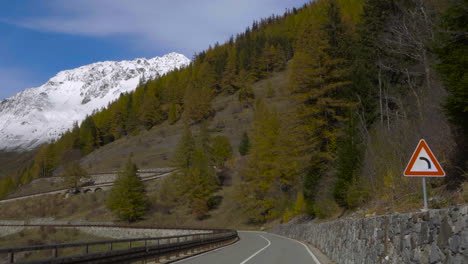 travelling to snow-capped mountains by road, crossing forest, following street signs.