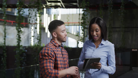 Happy-diverse-male-and-female-colleagues-using-tablet-and-talking-in-foyer