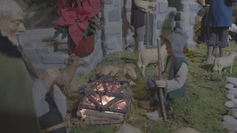 two shepherds warming themselves by the fire together with their sheep in a nativity scene