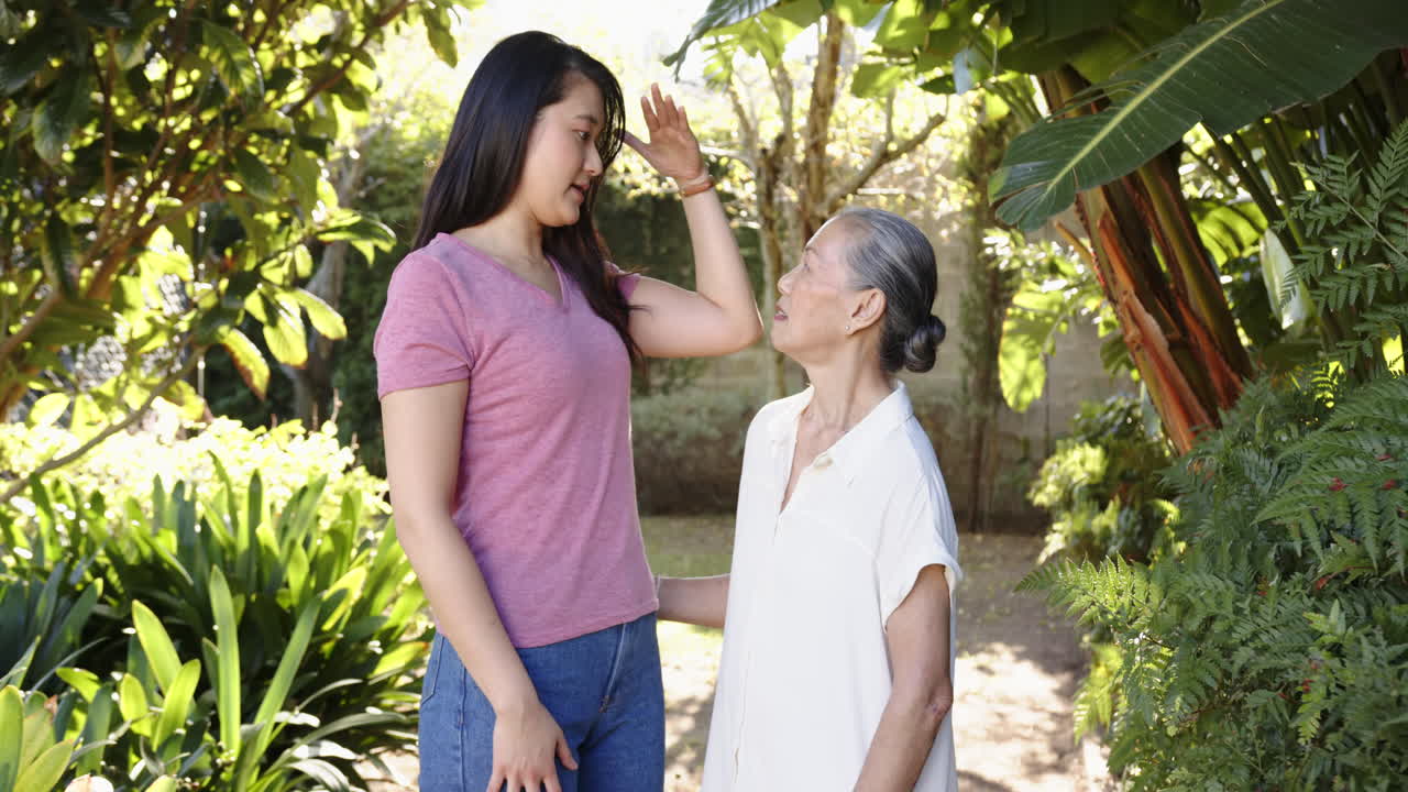 Smiling asian grandmother and granddaughter bonding in lush garden setting