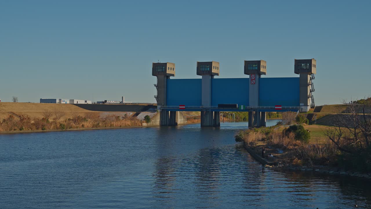 Un'inquadratura diagonale panoramica della chiusa Blue Iwabuchi. La moderna paratoia e il fiume Arakawa sono ripresi con un senso di profondità a Tokyo, Giappone.