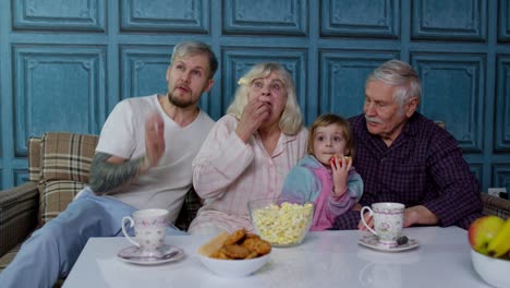 Familia-Multigeneracional-Asustada,-Viendo-Películas-De-Terror-En-Televisión,-Comiendo-Palomitas-De-Maíz-En-Casa