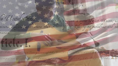 Mixed-race-father-and-son-playing-guitar-with-US-flag-waving-and-constitution-foreground