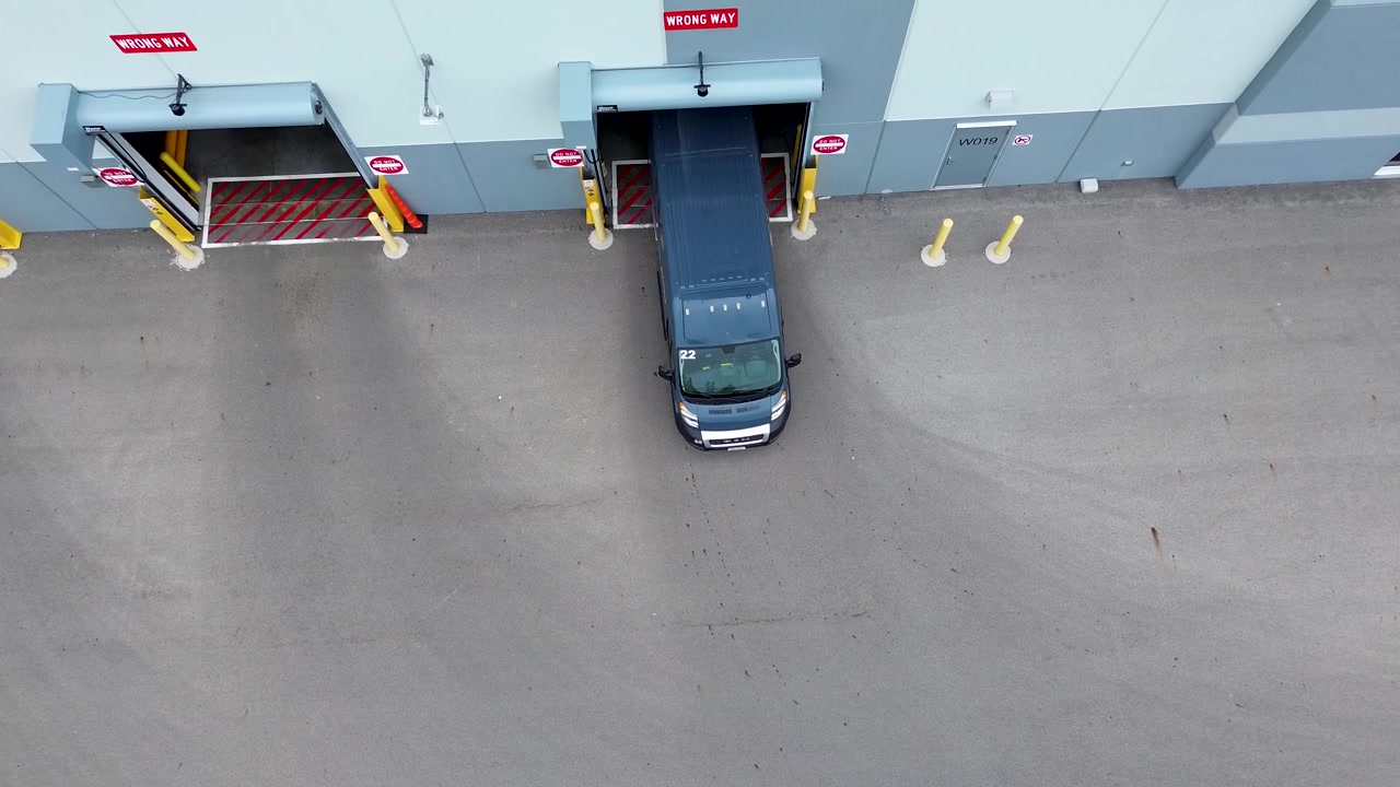 Amazon Vans pull out of Amazon warehouse, aerial drone, straight down