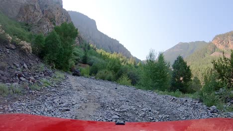 pov following a jeep on gravel covered alpine loop trail cut into the mountain side of the san juan mountains in colorado