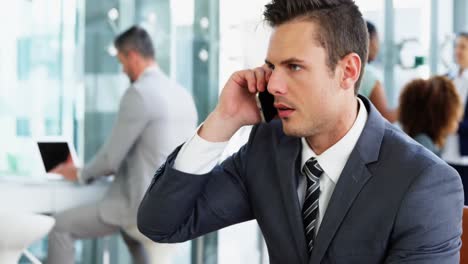 businessman picking up a call while working in laptop