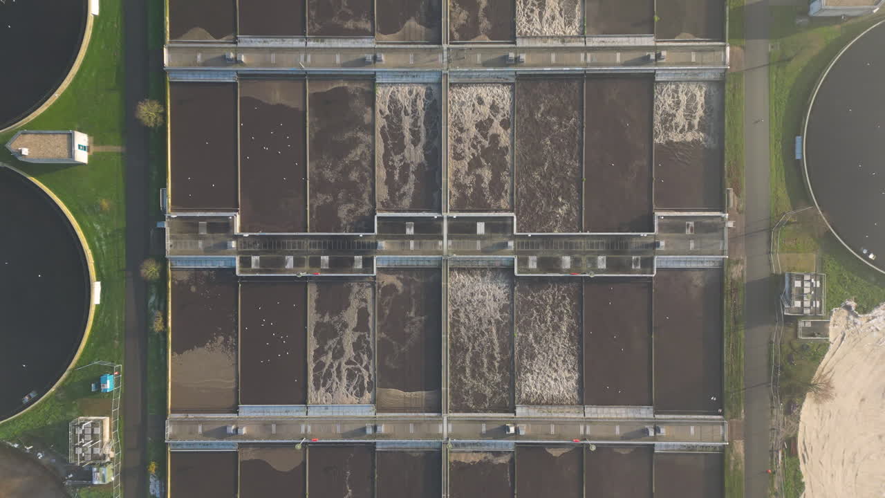Aerial view rising through clouds looking down over water treatment sewage plant