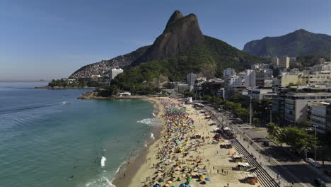 un avión no tripulado se eleva hacia atrás sobre la playa de praia do leblon, en el soleado río de janeiro.