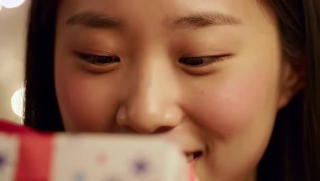 a young woman's delightful discovery: captivated by a special gift under twinkling lights, her joy radiates as she examines every detail with a bright smile